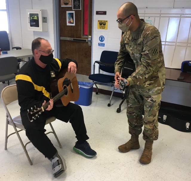 Spc. Jonathan Rodriquez teaches Lt. Col. Ken Sanders during a music lesson as part of the Adaptive Reconditioning Program. The 3rd Infantry Division Band provides volunteers to assist with an eight-week long Adaptive Reconditioning Program to teach guitar as part of recreational therapy. Photo by Sgt. Anthony Licata 