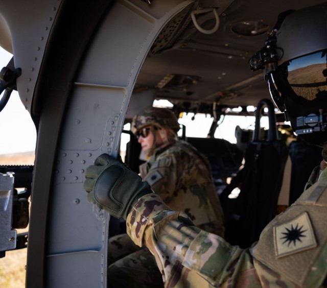 Staff Sgt. Kevin Novak, UH-60 Black Hawk Standardization Instructor, watches Chief Warrant Officer 3 Jennifer Collins, a UH-60 pilot, fire the M240H machine gun out of a UH-60M Black Hawk during ground fire familiarization at Fort Sill, Oklahoma,...
