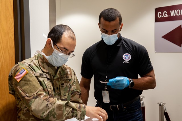 U.S. Army Spc. Zachary Burton, a Marion, Indiana, native and a nurse assigned to the 531st Hospital Center, and Daniel Vega, a Salinas, Puerto Rico, native and Federal Emergency Management Agency employee, review a patient’s vaccination card at...