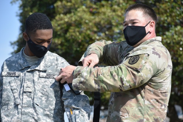 Staff Sgt. Miki Dodge, right, a combat medic specialist and noncommissioned officer in charge of family medicine at the BG Crawford F. Sams Army Health Clinic at Camp Zama, demonstrates how to use a tourniquet with Cadet Pvt. Ty Chavis during the...