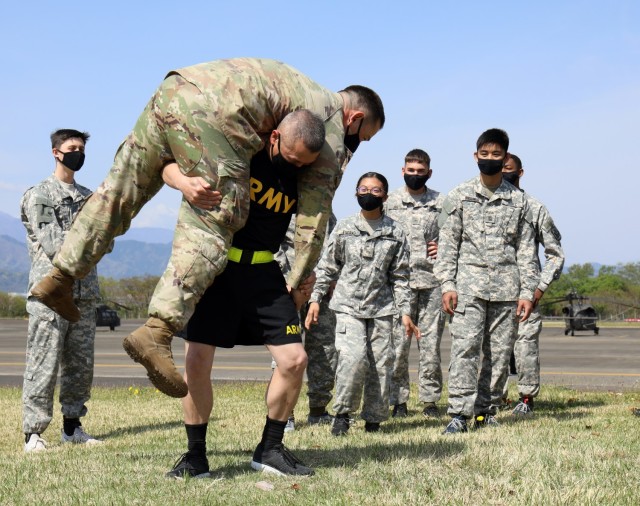 Retired Sgt. Maj. Danny Davis, Junior Reserve Officers’ Training Corps instructor, demonstrates a medical rescue carry with Staff Sgt. Miki Dodge, right, a combat medic specialist and noncommissioned officer in charge of family medicine at the...