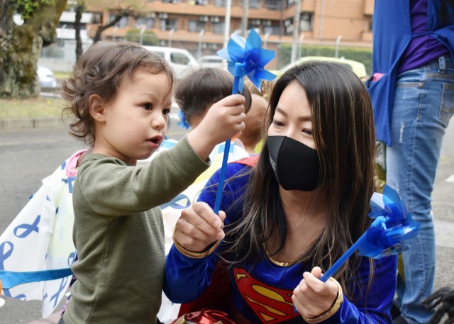 Sari Sugai, Exceptional Family Member Program manager for Army Community Service, helps Ezra Stallings, 2, plant a pinwheel at the Child Development Center at the Sagamihara Family Housing Area, Japan, April 9. Camp Zama Family and Morale, Welfare...