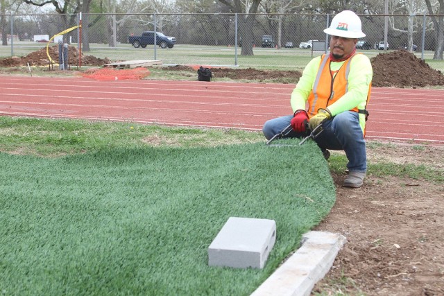 Carlos Nambo of Pro Turf Incorporated of Haslet, Texas, pulls slack out of a section of artificial turf April 9, 2021 on the infield of the Prichard Field track here. The synthetic multipurpose field will primarily be used for Army Combat Fitness...
