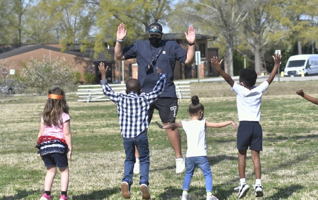 Jordan M. Fields, Child and Youth Services functional fitness instructor, leads a Child Development Center exercise session April 7 at the CYS athletics field. Fields has developed numerous programs for the children that include drills, exercises and games (photo by T. Anthony Bell).