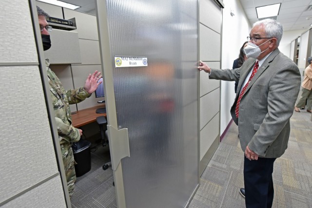 Maj. Ryan McMahon, Professor of Surgery and Director of Basic Life Support, demonstrates the sliding door of his new office partition to Mr. J.M. Harmon III, Deputy to the MEDCoE Commanding General.