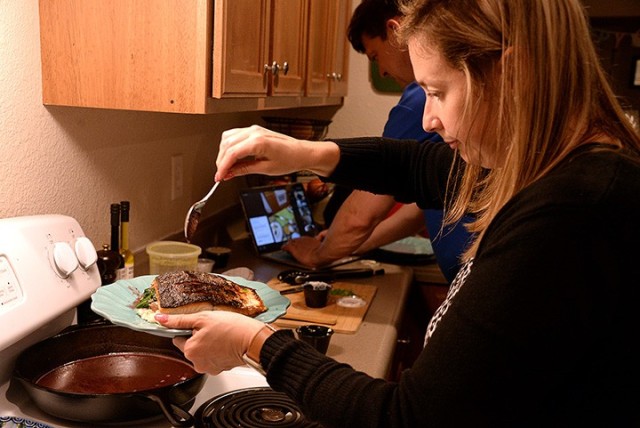 Fort Leavenworth Spouses’ Club cooking class participant Liz Stone, FLSC special events chairperson, drizzles beurre rouge sauce over salmon to complete the dish while her husband, Maj. Ryan Stone, Command and General Staff Officer Course...