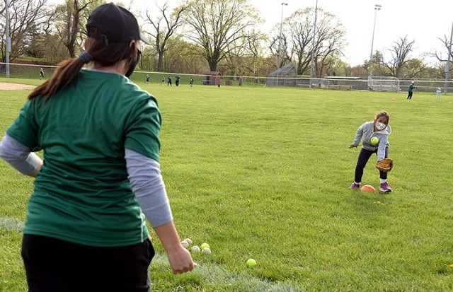 Mallory Barnhouse, Child and Youth Services Youth Sports and Fitness fitness specialist, sends a ball toward 8-year-old Isabella Bowman for her to practice catching a pop fly during the CYS Youth Sports and Fitness Spring Youth Baseball Skills...