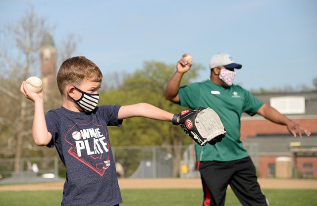Five-year-old Chris Farrington mimics Patrick Shelton, Child and Youth Services Youth Sports and Fitness director, in ready position at the catching-and-throwing station of the Spring Youth Baseball Skills Clinic April 12 at Doniphan Field. The...