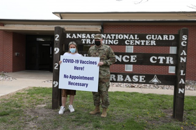 Maj. Michael Billings, Kansas Training Center battalion executive officer and Hayley Samford, marketing and community outreach associate with the Salina Family Healthcare Center, pose with a sign advertising the COVID-19 vaccine clinic held at the...