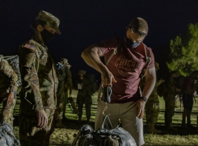 (Left) Pvt. 1st Class Jacquelyn Shea, Soldier student, 305th Military Intelligence Battalion, watches as Blake Rydalch, volunteer, weighs her rucksack in at 4:45 a.m. April 10, 2021 at Brown Parade Field, Fort Huachuca, Ariz. More than 250 Soldiers and civilians assembled on Brown Parade Field for the opening ceremony of the march sponsored by the 111th Military Intelligence Brigade and the Directorate of Family, Morale, Welfare and Recreation. The Bataan Memorial Death March is a challenging and grueling march that tests both mental and physical abilities. For the 2021 virtual experience, marchers can choose between the full 26.2-mile marathon length or a 14.2-mile honorary distance.