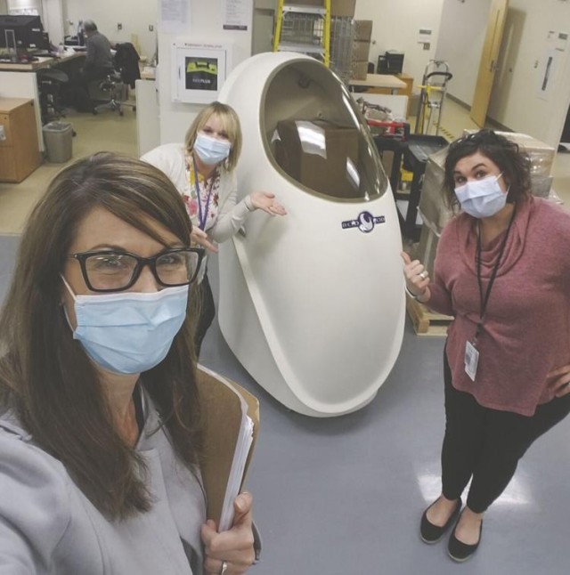 From left, Nicole Leth, Armed Forces Wellness center lead educator; and health educators Kellie Hundemer and Amber Scharbo next to the Bod Pod.