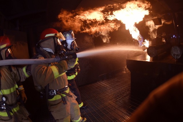 Spc. Brian McClure and Pvt. Sidney Little – 88K Watercraft Operator Course students – direct water toward flames in the fire training facility under the guidance of instructor Donald Jones during training April 16 at Joint Base Langley-Eustis....
