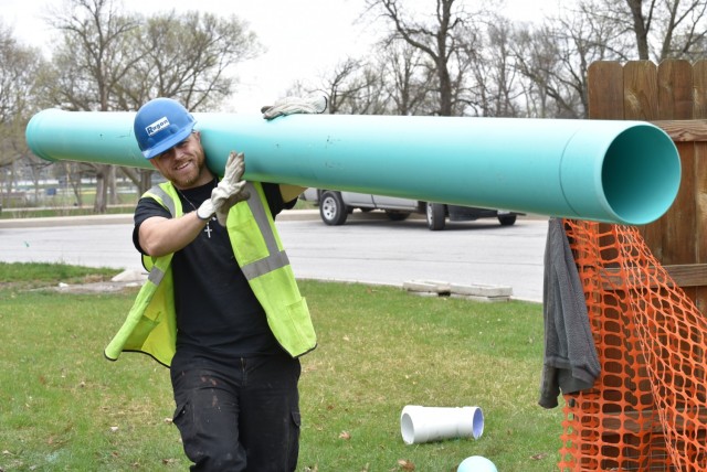 Dallas Wild, heating ventilation and air Conditioning technician, carries pipes for a Department of Public Works project to install drains that will connect to the storm sewers to keep water from collecting in the backyards of residences, April 9 in the RIA housing area on Walker Drive.