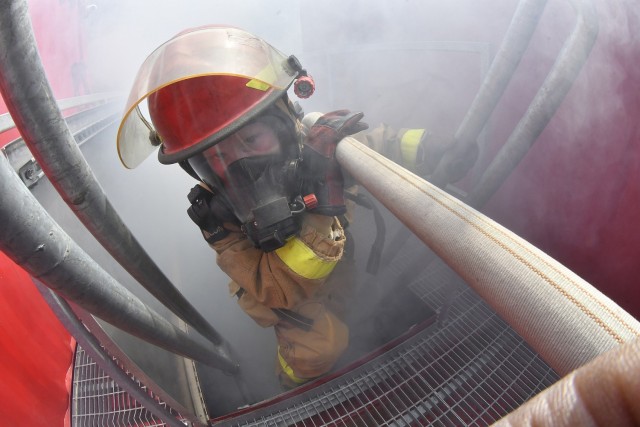 With the hose resting on her shoulder, Pvt. Sidney Little lowers herself into the chamber following team members during 88K watercraft operator firefighter training April 16 at the Transportation School, Joint Base Langley-Eustis.