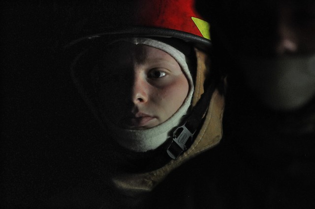 Pvt. Sidney Little, an 88K Watercraft Operator Course student, listens to the brief with other students in the darkness of the fire trainer April 16 at Joint Base Langley-Eustis. Little and her classmates would later don equipment to fight flames...