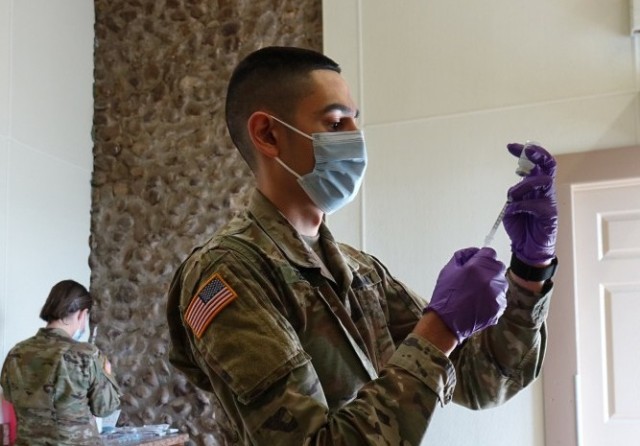 Spc. Matthew Bernal, a medic in the Texas Army National Guard, inspects vials of a COVID-19 vaccine in Cuero, Texas, Jan. 29, 2021, during a vaccination pilot program to bring vaccines to rural areas in Texas. Bernal said that he joined the Guard...