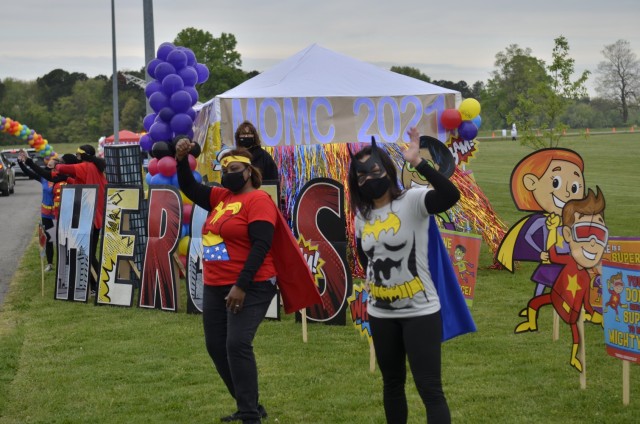 Deon Williams, left, and Camelly Lopez, lead child and youth program assistants at Child Care Development Center 1, cheer on military children April 17 during Kidsfest: Magical Drive-thru, hosted by Morale, Welfare and Recreation at the division...