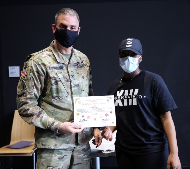 Col. Michael R. Kaloostian, 2nd Theater Signal Brigade Commander, presents Deziar Tezeno with a Certificate of Excellence for her contributions to the Wiesbaden High School’s Air Force Association United States CyberPatriot program. Members of...