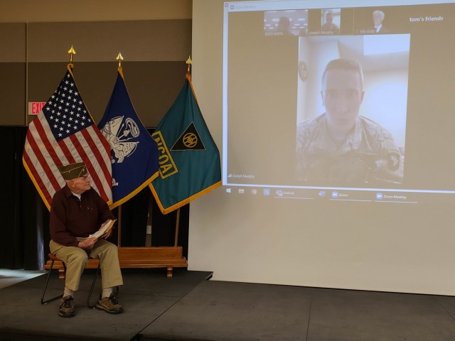 Tom Sitter, World War II veteran and Days of Remembrance speaker for the 86th Training Division at Fort McCoy, Wis., is introduced by his grandson, Capt. Joseph Murphy, special assistant, United States Attorney at Fort Campbell, Ky. over a video...