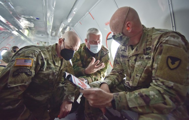 Maj. Gen.Elder Giraldo, chief of operations for the Columbian Army, center, briefs Brig. Gen. Douglas Lowrey, commander of U.S. Army Security Assistance Command, during a quick huddle inside a Colombian aircraft flying over Colombia, 5 April 2021....