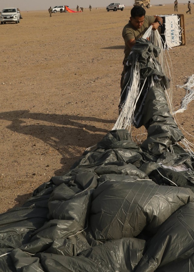 Rigger Spc. Andres Sanchez with the Fort Bragg, North Carolina, based 151st Quartermaster Company, deployed to the U.S. Central Command area of responsibility in support 1st Theater Sustainment Command, collects the rigging lines from one of the four parachutes that each successfully carried bundles within 75 meters of the target at the Camp Buehring, Kuwait, drop zone April 22, 2021 using the Joint Precision Air Delivery System, or JPADS. Sanchez said he appreciated the chance to participate in the real-world exercise. (U.S. Army photo by Staff Sgt. Neil W. McCabe)