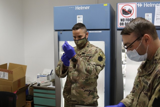 Sgt. Austin Peters, left, and Staff Sgt. Dave Yanetti, both medical specialists with the 28th Expeditionary Combat Aviation Brigade, prepare syringes with the COVID-19 vaccine at a medical clinic in the 28th ECAB's area of operations in the...