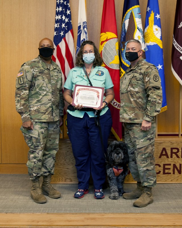 Brooke Army Medical Center Commanding General Brig. Gen. Shan Bagby and Command Sgt. Maj. Thurman Reynolds present Kris Blair and therapy dog Huckleberry are certificate of appreciation for their volunteer service during a volunteer recognition ceremony at BAMC, Fort Sam Houston, Texas April 21, 2021. Blair and Huckleberry also participated in BAMC’s first staff Resiliency Week April-19-23, 2021. (U.S. Army Photo by Garron Webster)