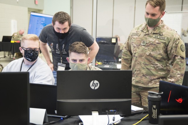 U.S. Army Staff Sgt. Paul Coffy (center, seated) views the status of the virtual exercise environment as two West Virginia University students and U.S. Army Staff Sgt. Adam Brenner (right) observe. For Locked Shields 2021, the West Virginia...