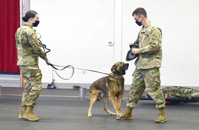 Spc. Monica Wilson (left) holds the leash of military working dog, Ben, as they demonstrate a take down on Pvt. Christopher LaBelle.
