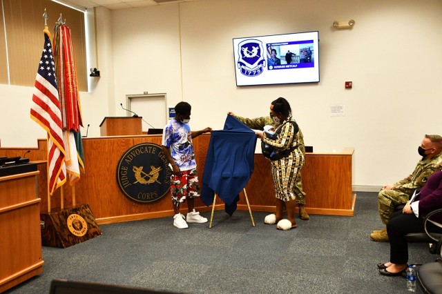 Desmond Metcalf, (left) Sgt. Maj. Howard Metcalf’s son, works with Jasmine Roberts, (right) Desmond’s fiance, their son, Khalil, 3 months old, and Sgt. Maj. Osvaldo Martinez, (behind Jasmine) 13th Regimental command sergeant major of the U.S. Army JAG Corps, as they unveil the plaque dedicating the Fort Polk Courthouse in Metcalf’s name.
