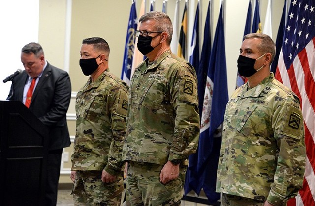 Incoming Combined Arms Center and Fort Leavenworth Command Sgt. Maj. Stephen Helton, CAC and Fort Leavenworth Commanding General Lt. Gen. James Rainey, and outgoing CAC and Fort Leavenworth Command Sgt. Maj. Eric Dostie stand at the front the room...