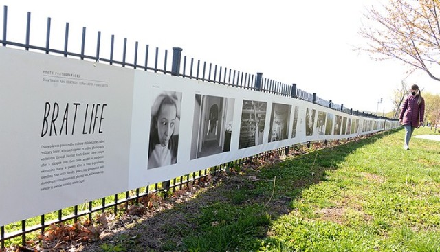 "To Be At War" workshop mentor Bethany Kidd looks at workshop participants' photography, displayed along the Missouri River, before a brief ceremony to kick off the "To Be At War" community photography exhibit April 22 at Leavenworth Landing Park....