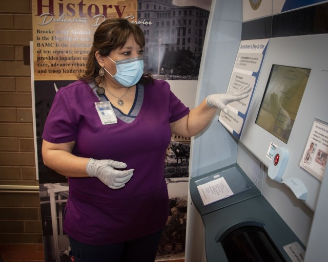 Rose Guillen, pharmacy technician, demonstrates the proper use of new express prescription kiosk at Brooke Army Medical Center, Fort Sam Houston, Texas, March 31, 2021. The new kiosks will allow patients to pick up prescriptions even when the pharmacy is closed. (U.S. Army photo by Jason W. Edwards)