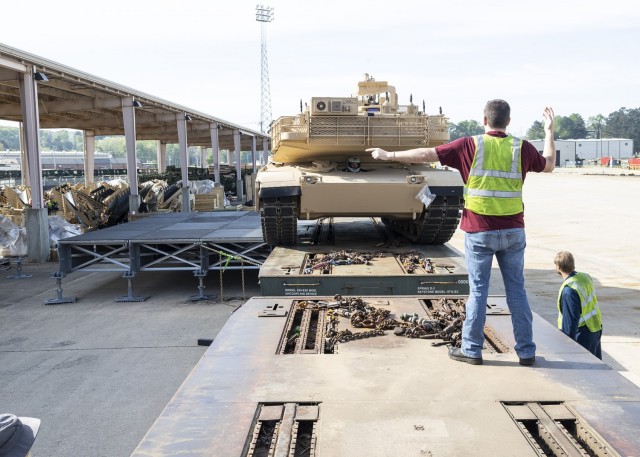 Landon Magouryk and Wayne Hubbard (right) guide an M1A1 Abrams tank onto a railcar using the RAIL turn pad platform configuration during a demonstration at Anniston Army Depot.