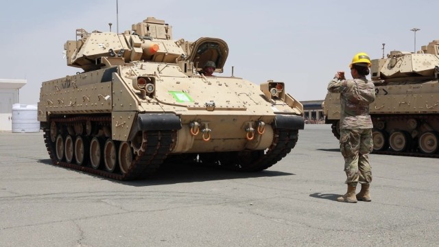 Capt. Shayna Taylor, officer in charge of the port support element, 1st Battalion, 35th Armored Regiment, 2nd Brigade Combat Team, 1st Armored Division, ground guides the driver of an M2/A2 Bradley Fighting Vehicle to the proper staging area as...