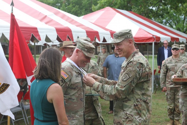 Maj. Gen. Ken Kamper, Fires Center of Excellence and Fort Sill commanding general, enjoys the moment as he drapes the Legion of Merit on Brig. Gen. Phil Brooks while talking with Brooks’ wife, Lori, left.