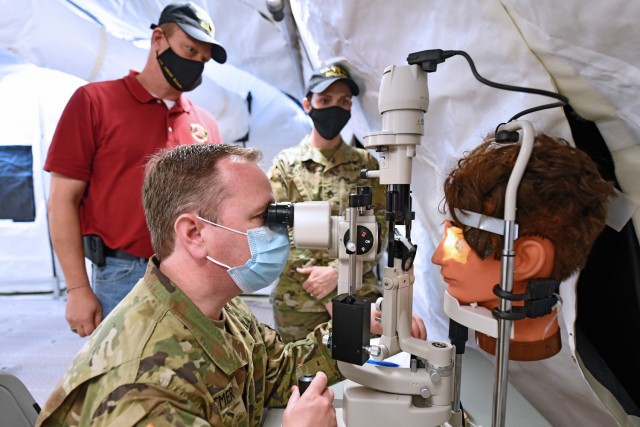 Charles Lohsandt and Staff Sgt. Tara Laramee with the U.S. Army Medical Test and Evaluation Activity look on as Maj. Sean Lutmer, an Ophthalmologist at Fort Benning, tests the Ophthalmic Slit Lamp.