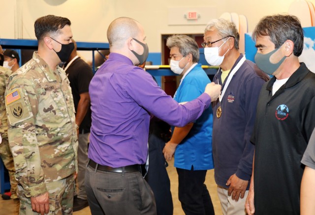 Rick Bosch, center, director of Camp Zama’s Family and Morale, Welfare and Recreation, presents Kaoru Mogi, a maintenance employee, with an FMWR gold medal for his work on the new Outdoor Recreation facility at Camp Zama, Japan, April 29. Col....