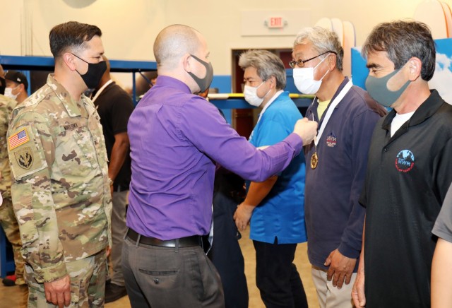 Rick Bosch, center, director of Camp Zama’s Family and Morale, Welfare and Recreation, presents Kaoru Mogi, a maintenance employee, with an FMWR gold medal for his work on the new Outdoor Recreation facility at Camp Zama, Japan, April 29. Col. Thomas Matelski, left, commander of U.S. Army Garrison Japan, congratulates employees with Bosch.