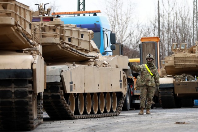 A U. S. Army Soldier assigned to the 1st Armored Brigade Combat Team, 1st Cavalry Division, guides M1 Abrams Main Battle Tanks at Parsburg, Germany, in preparation for transfer to Poland, Mar. 13, 2021.