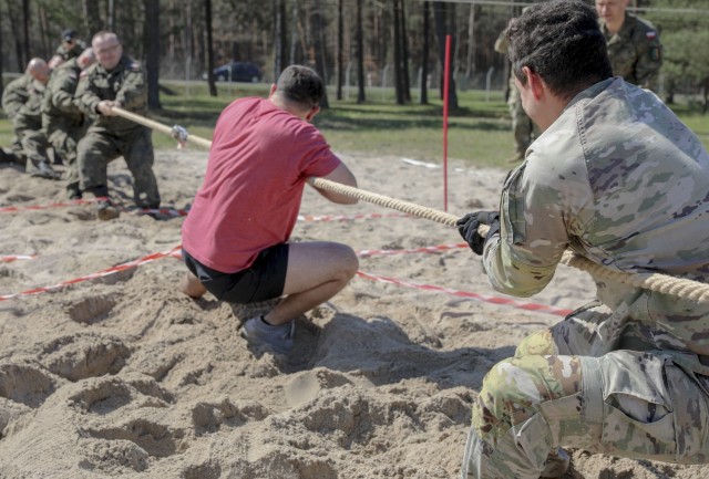 1st Lt. Nicholas Maio (pictured in uniform), executive officer, Headquarters and Headquarters Company, 1st Armored Brigade Combat Team (IRONHORSE) tugs on the rope with fellow IRONHORSE Troopers against soldiers from the 11th Armored Cavalry Division – Poland during a joint sports day between the U.S. and Polish at Zagan, Poland, April 27. The events, designed to build camaraderie, test fitness and strengthen partnerships, included 4x 400 meter relays, volleyball, weightlifting competitions, and a warrior fitness challenge. The sports day between IRONHORSE Troopers and their Polish counterparts is a part of Atlantic Resolve, where approximately 6,000 Soldiers are participating in nine-month rotations, enabling the U.S. to enhance deterrence, increase readiness and support NATO. (Photo by Army Staff Sgt. Christopher “Ham” Hammond)