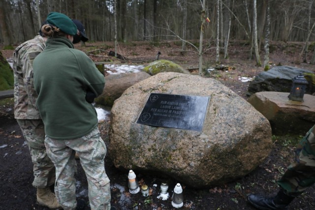 Capt. Spenser Swafford, Fire Support Officer assigned to 2nd Battalion, 8th Cavalry Regiment, and Lithuanian Liaison Officer Lt. Emile Mazeikaite, Griffin Brigade, read a stone marker placed in the forest Lithuanian freedom fighters occupied for...