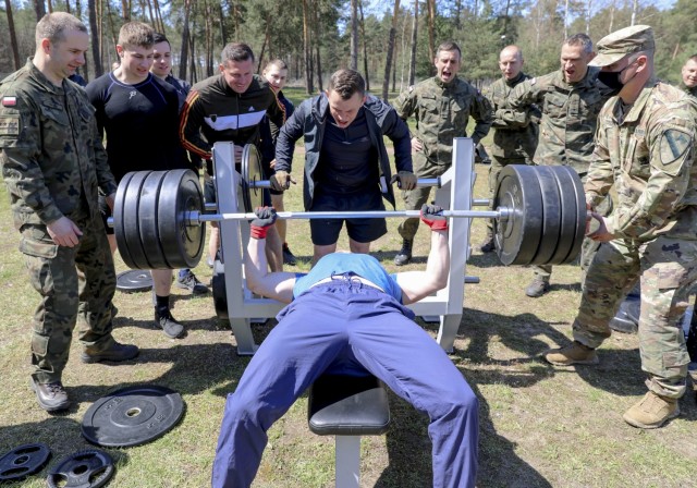 Sgt. 1st Class Kevin Cremo, 1st Armored Brigade Combat Team, helps "spot" as a soldier with the 11th Armored Cavalry Division – Poland prepares to bench-press during a joint sports day between the U.S. and Polish at Zagan, Poland, April 27. The events, designed to build camaraderie, test fitness and strengthen partnerships, included 4x 400 meter relays, volleyball, weightlifting competitions, and a warrior fitness challenge. The sports day between IRONHORSE Troopers and their Polish counterparts is a part of Atlantic Resolve, where approximately 6,000 Soldiers are participating in nine-month rotations, enabling the U.S. to enhance deterrence, increase readiness and support NATO.