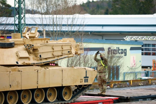 A U. S. Army Soldier assigned to the 1st Armored Brigade Combat Team, 1st Cavalry Division, guides an M1 Abrams Main Battle Tank onto a railcar in preparation for transfer to Poland, at Parsburg, Germany, Mar. 13, 2021.