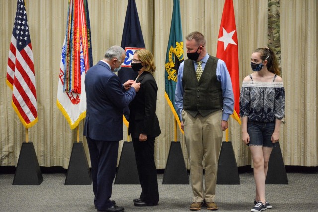 John Hall, Headquarters Department of the Army G4 principal deputy (left), presents Sydney Smith, Army Logistics University president, with the senior executive service pin Friday, April 30, 2021, at the Army Logistics University Green Auditorium. Smith's husband, Tim, and daughter, Molly, watch the presentation. Members of the SES serve in the key positions just below the top presidential appointees and alongside general officers.