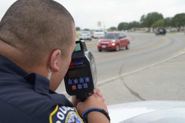 Officer Marcelo Aguillon, 902nd Security Forces uses his speed laser equipment to record vehicle speeds July 9 at Joint Base San Antonio-Randolph. (U.S. Air Force photo by Joel Martinez)