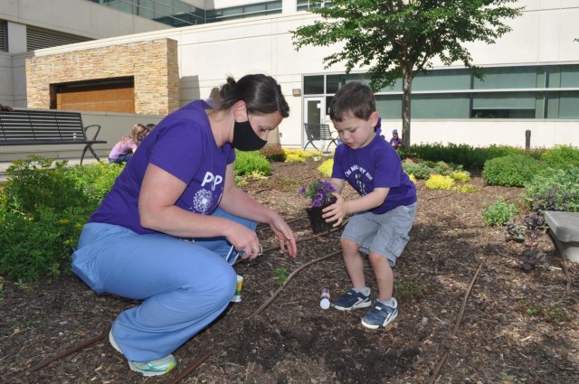 Martin Army Community Hospital Pediatrician Maj. Jessica Aguilar plants a purple flower with her son Axel as part of BMACH's Month of the Military Child celebration.