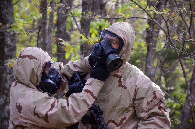 Competitors complete a buddy check to ensure their chemical protective clothing is properly secured and ready for follow-on operations at Training Area 125.