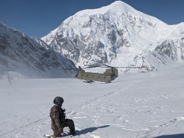 A Soldier from 1st Battalion, 52nd Aviation Regiment, based out of Fort Wainwright, watches as a second CH-47 Chinook helicopter touches down at Denali base camp. The Soldiers were assisting the National Park Service in bringing gear and supplies to the camp for climbing season. 