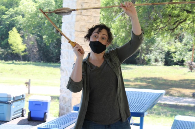 Coral Eginton, an archaeologist, shows how prehistoric hunters used an atlatl to increase the range of their spears at the Archaeology station during the U.S. Army Environmental Command Nature Walk held for about 140 kindergarteners from the Fort Sam Houston Elementary School.
